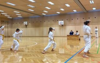 Vier Karatekas beim Kihon während der Prüfung zum 7. Kyu unter den Augen der Prüfer